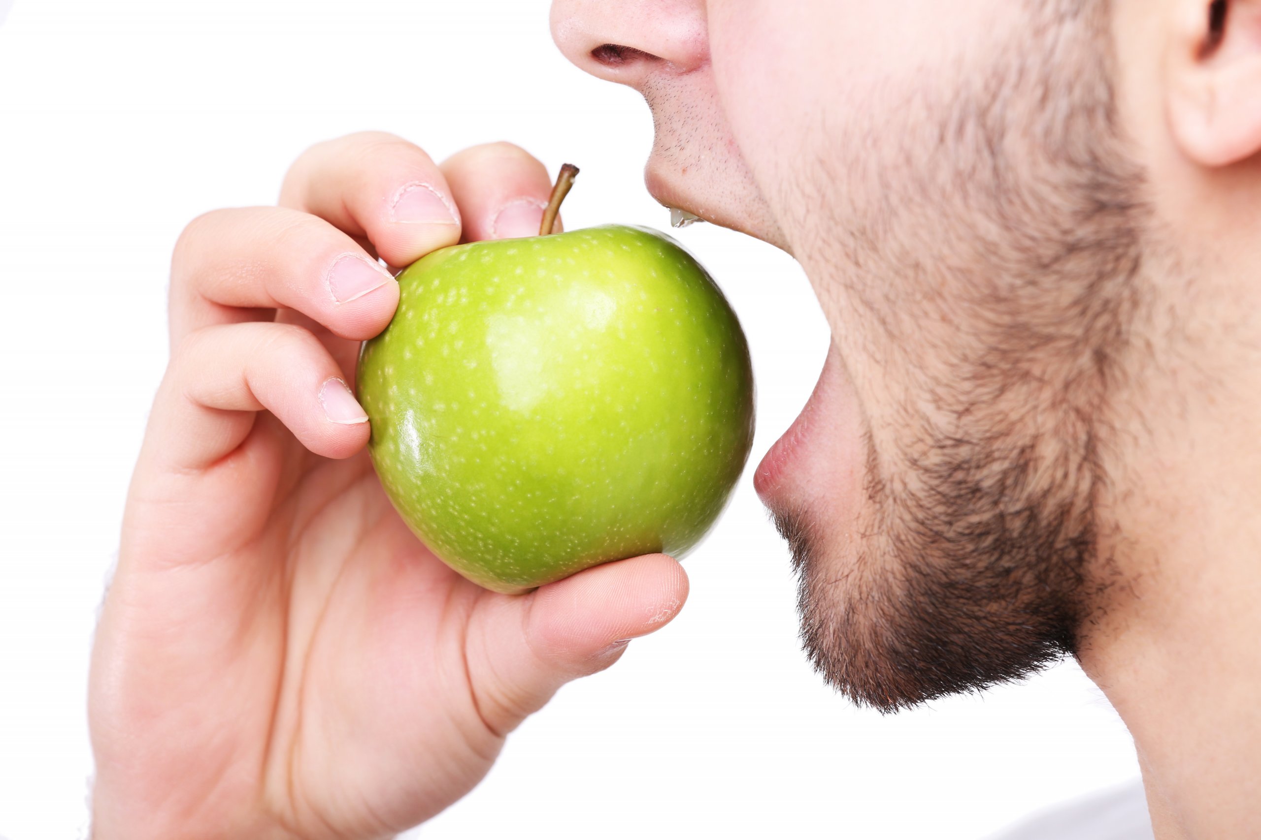 Man biting fresh green apple with healthy teeth isolated on white background